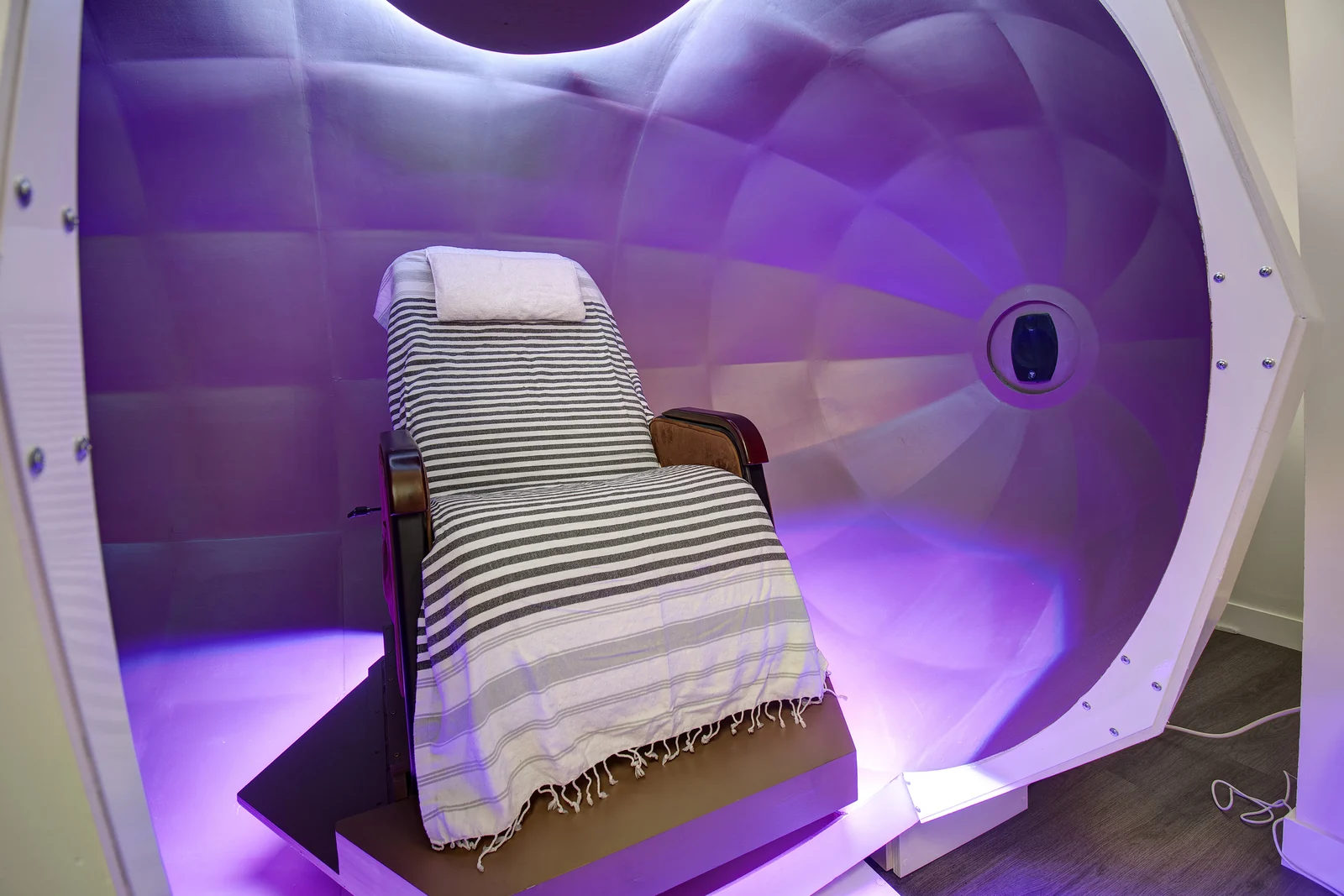 The reclining chair inside the Harmonic Egg, made up with a striped blanket and a folded towel.
